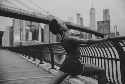 Side view of woman exercising on promenade in city