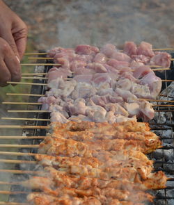 Cropped image of person preparing food on barbecue grill