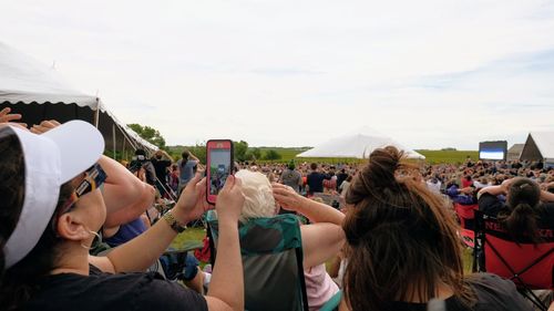 Crowd at music concert against sky