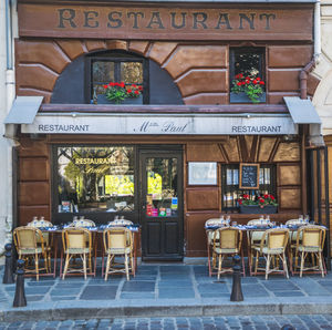 Chairs and tables at sidewalk cafe in city