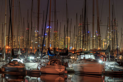 Sailboats in harbor by buildings against sky at st kilda at night