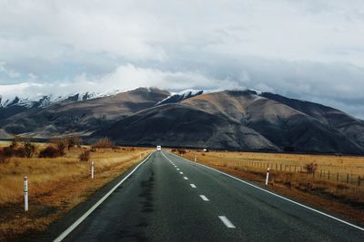 Road leading towards mountains against sky