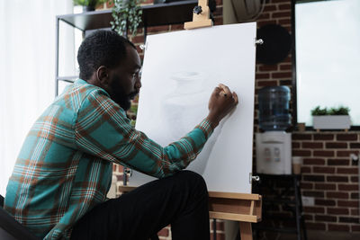 Side view of man sketching at home