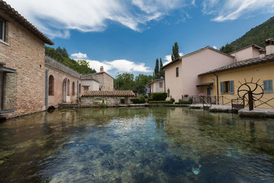 Houses by river and buildings against sky