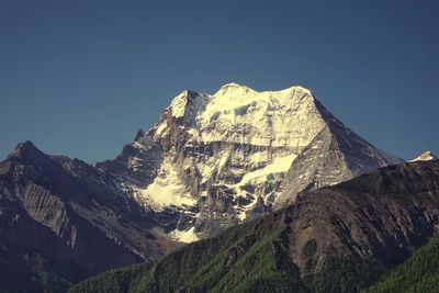 Low angle view of snowcapped mountain against blue sky