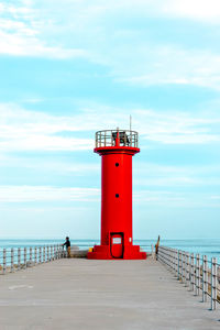 Lighthouse by sea against sky