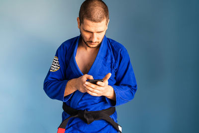 Man holding mobile phone against blue sky