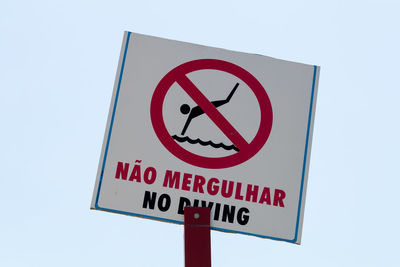 Close-up of no diving sign board against clear sky