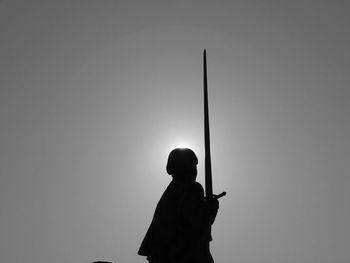 Silhouette man using mobile phone against clear sky