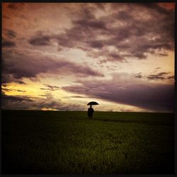 Man standing on field against cloudy sky
