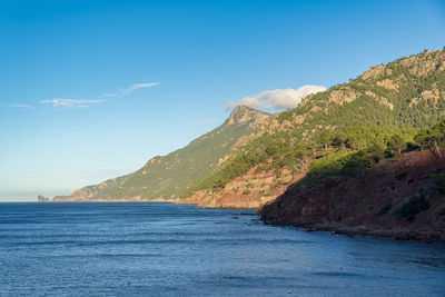 Scenic view of sea and mountains against blue sky