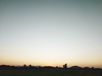 Scenic view of silhouette field against clear sky during sunset