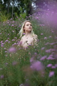 Woman standing on purple flowering plants on field