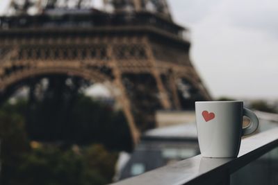 Coffee cup on railing with eiffel tower seen in background