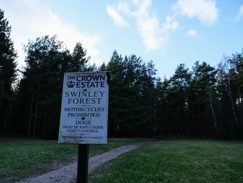 Information sign on field against sky