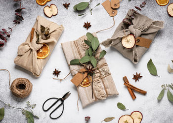 Christmas presents wrapped in linen cloth decorated with cinnamon sticks, dry apple, orange slices. 