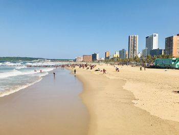 People on beach against clear sky