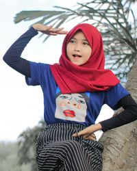 Portrait of young woman standing against wall
