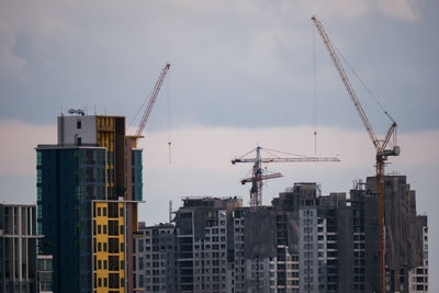 Cranes at construction site against sky in city