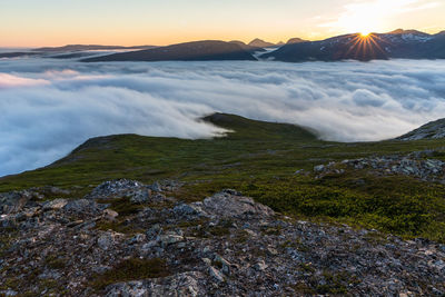 Clouds covering mountains against sky during sunrise