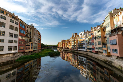 Canal amidst buildings against blue sky in city