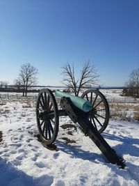 Bicycle on snow covered field against sky