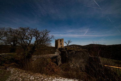 Old ruin on field against sky at night