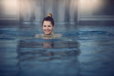 Portrait of smiling young woman swimming in pool