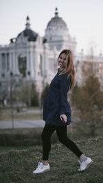 Portrait of smiling young woman against built structure