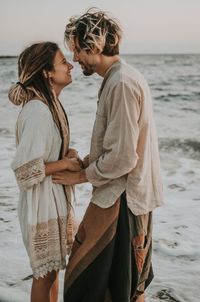 Side view of couple standing at sea shore