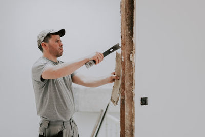 A man working with a crowbar in a doorway.