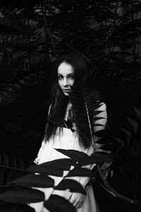 Portrait of young woman standing against tree