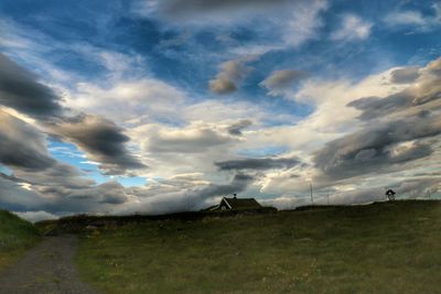 Scenic view of grassy field against cloudy sky