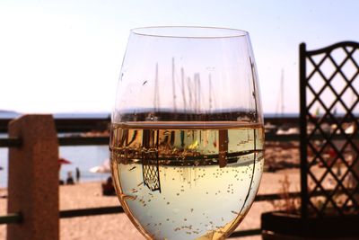 Close-up of beer glass on table against sky