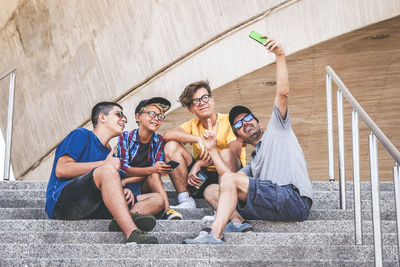 Man taking selfie with smiling friends using smart phone on steps