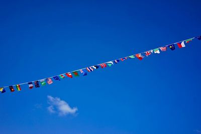 Low angle view of bunting flags against blue sky