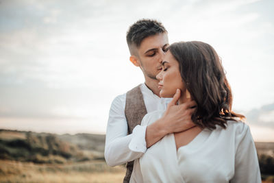 Couple kissing against sky