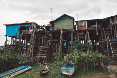 Low angle view of abandoned houses against cloudy sky