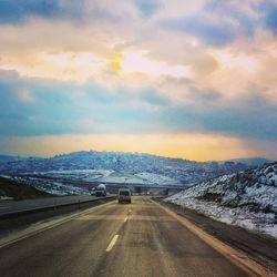 Road passing through landscape against cloudy sky