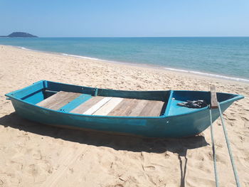 Boat moored on beach against sky