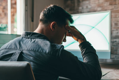 Side view of young man using mobile phone while sitting at home