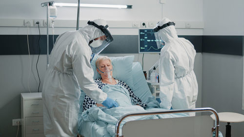 Doctors wearing hazmat suit examining patient in clinic