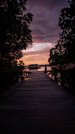 Footpath by sea against sky during sunset