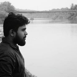 Profile view of young man looking away against lake