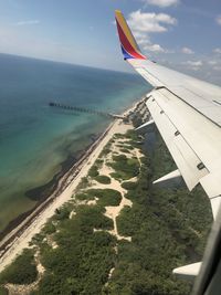 Airplane flying over sea against sky