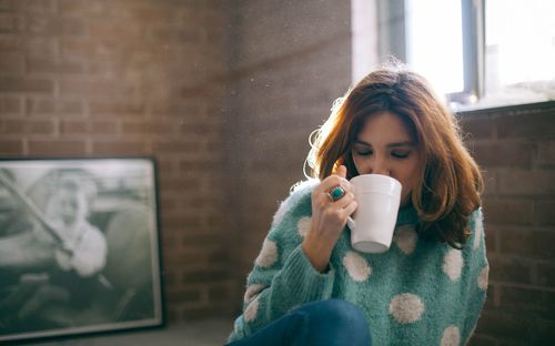 Mid adult woman drinking coffee at home