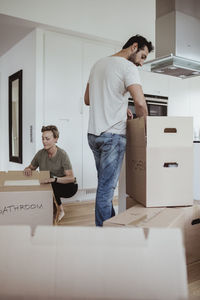 Male and female partners unpacking cardboard boxes in new house