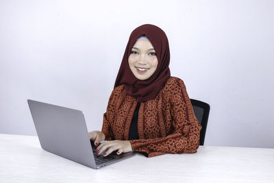 Portrait of smiling woman sitting on laptop