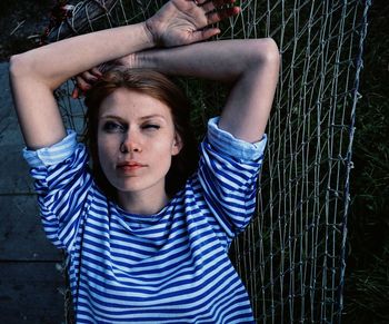 Portrait of beautiful woman winking while resting on hammock