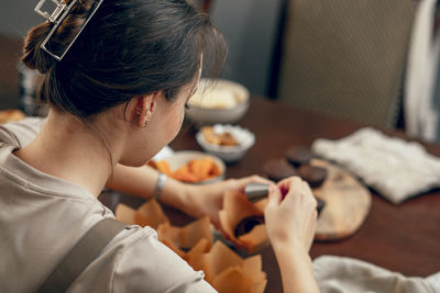 Young woman makes indentations in cupcakes, concept of baking at home in  kitchen, copy space